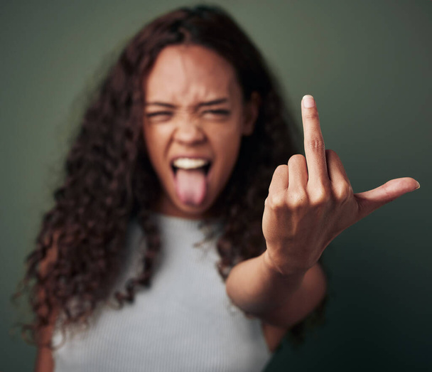 Dont push my buttons. Studio shot of a young woman showing her middle finger against a green background - Foto, Imagen