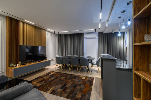 Luxusní obývací pokoj s jídelním nebo banketovým stolem a šedou kuchyní v studio apartmánu interiér - Fotografie, Obrázek