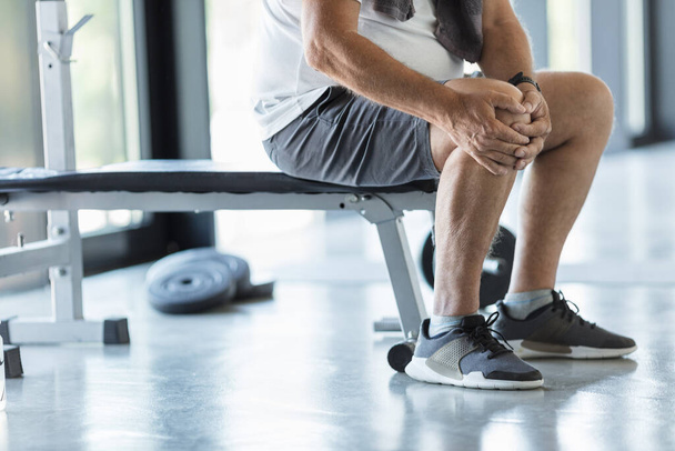 Active senior man in gym with knee injury - Фото, изображение