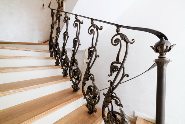 wooden stairs with metal wrought iron railings in a new house - Photo, image