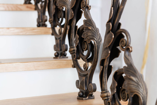 wooden stairs with metal wrought iron railings in a new house - Fotó, kép