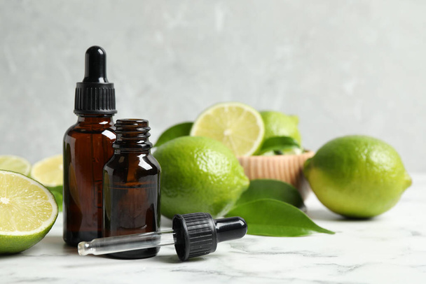 Lime essential oil and citrus fruits on marble table - Фото, зображення