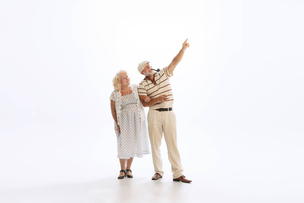 Couple in love. Portrait of retro style people, senior man and woman in vintage attire walking isolated on white background. Concept of relationship psychology, age, fashion - Φωτογραφία, εικόνα