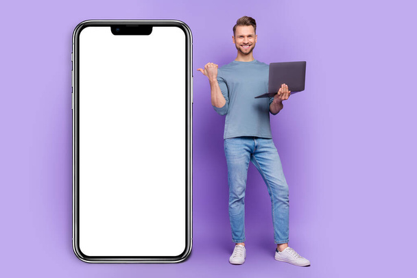 Photo of busy positive guy dressed grey shirt writing modern gadget pointing empty space isolated purple color background. - Φωτογραφία, εικόνα