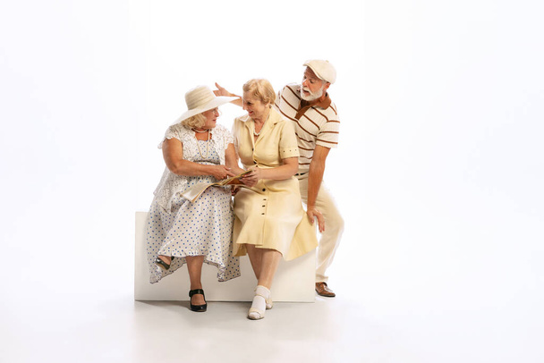 Friendly gatherings. Handsome senior man and two charming women in vintage retro style outfits isolated on white background. Concept of relations, family, 1960s american fashion style and art. - Foto, afbeelding