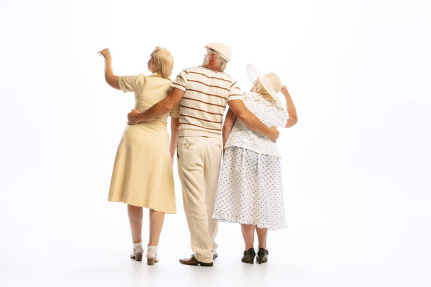 Dating. Handsome senior man and two charming women in vintage retro style outfits isolated on white background. Concept of relations, family, 1960s american fashion style and art. - 写真・画像