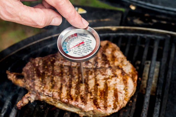 Beef blade steak grilling on barbecue grill plate with meat thermometer. Backyard BBQ grill cooking meat. - Zdjęcie, obraz