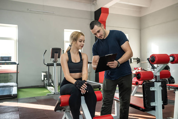 The trainer assists with female client doing workout in the gym. exercise lifestyle - Fotoğraf, Görsel