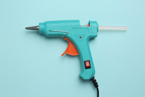 Glue gun with stick on turquoise background, top view - Foto, immagini