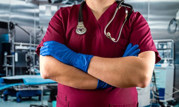 orvos vagy nővér piros egyenruhában sztetoszkópos stanzióval a sürgősségin. Egészségügyi és gyógyszerészeti ellátás - Fotó, kép