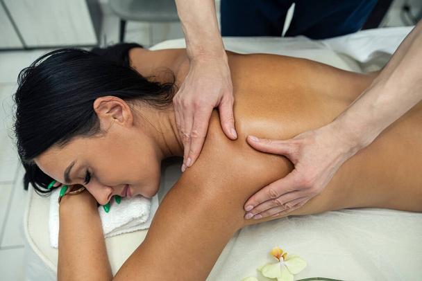 Закрыть руки терапевта, делающего массаж шеи женщинам в спа-салоне. Концепция косметики. - Фото, изображение