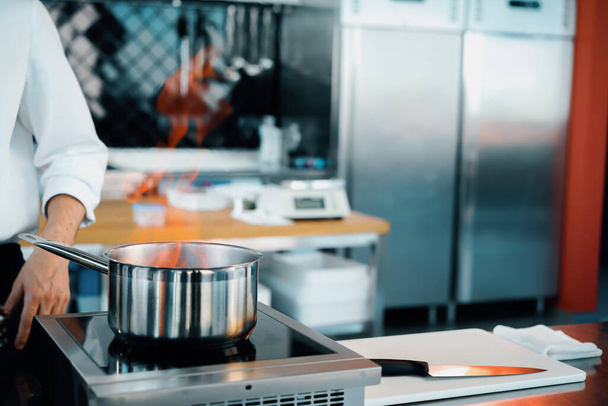 Επαγγελματική κουζίνα του εστιατορίου, κοντινό πλάνο: φωτιά από την κατσαρόλα, διαδικασία παρασκευής της σάλτσας - Φωτογραφία, εικόνα
