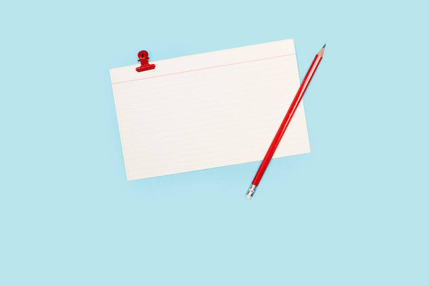 Blank striped paper note with a red pencil on a light blue background with copy space - Photo, Image