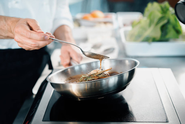 Профессиональная кухня ресторана, крупный план: повар мужского пола готовит филе миньон на сковородке - Фото, изображение