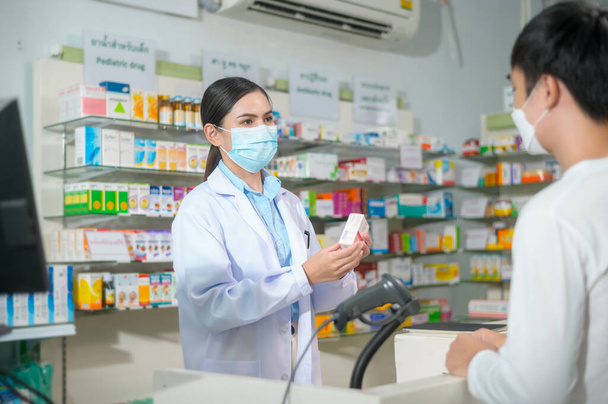 A Portrait of female pharmacist wearing face mask in a modern pharmacy drugstore. - 写真・画像