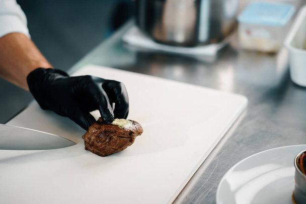 Professional kitchen of a restaurant, close-up: male chef cuts a ready-made delicious filet mignon - Photo, Image