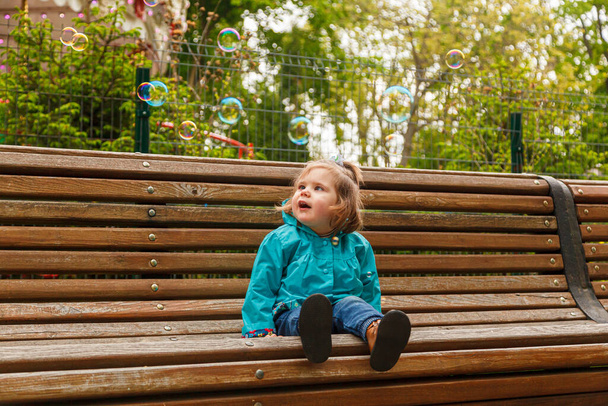 portrait of a little girl in the park on a bench catches soap bubbles close-up - Foto, immagini