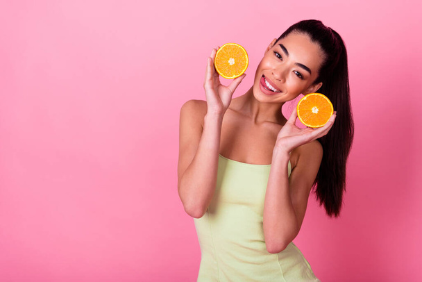 Photo of cunning pretty woman wear yellow dress holding citrus halves empty space isolated pink color background. - Фото, зображення