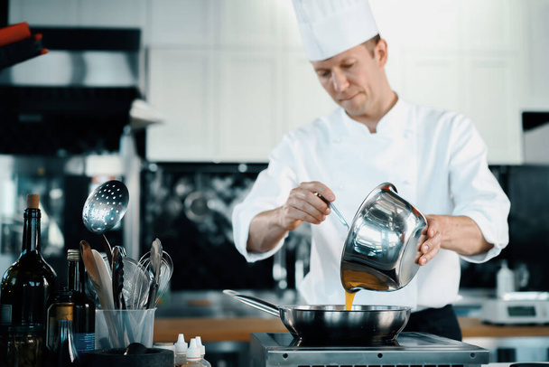 Professional kitchen of a restaurant, close-up: a male chef prepares french omelette in a frying pan - Valokuva, kuva
