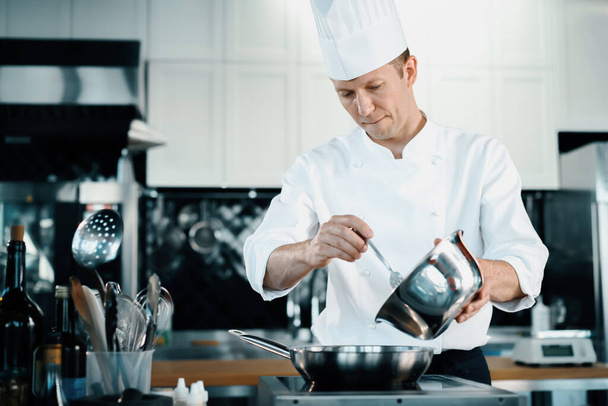 Επαγγελματική κουζίνα ενός εστιατορίου, κοντινό: ένας αρσενικός σεφ ετοιμάζει γαλλική ομελέτα σε ένα τηγάνι - Φωτογραφία, εικόνα