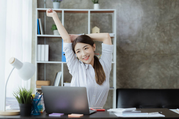 Working woman relaxing, a businesswoman in office, she is relaxing after working hard for a long time, causing fatigue and stress to take a break, she has office syndrome. Hard work concept. - 写真・画像