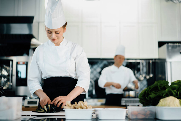 Professional restaurant kitchen, woman chef cuts a zucchini - 写真・画像
