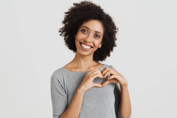 Young black woman smiling and making heart gesture isolated over white background - Foto, imagen
