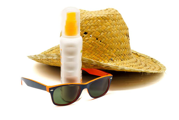 Close-up view of a straw hat, suntan lotion, beach towel and sunglasses. Summer vacations, sun protection and sun safety. - Fotografie, Obrázek