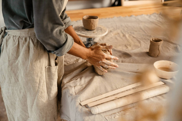 Young black ceramist woman wearing apron sculpting in clay at her workshop - Valokuva, kuva