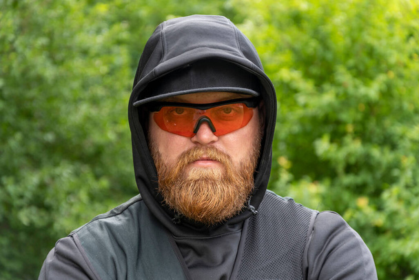 Portrait of a man with a beard 30-35 years old wearing glasses for shooting against the background of nature. - Foto, immagini