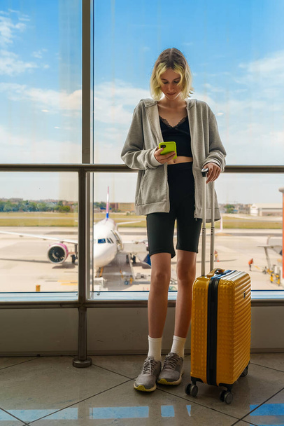 Teenage girl is waiting for her flight at the airport. - Foto, Imagen