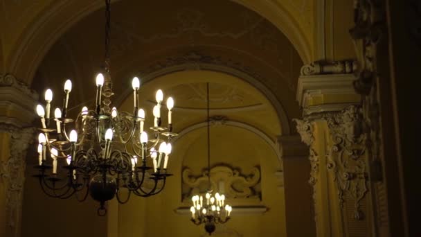 Zwarte metalen kroonluchter in barokke stijl met plafond en kaars gloeilampen. Hoge kwaliteit foto - Video