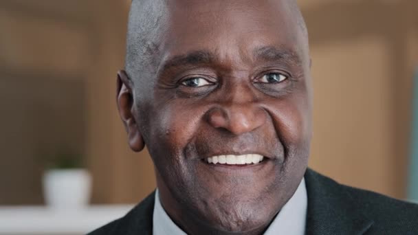 Close up happy male face 60s businessman elderly African American man grandpa satisfied client dentistry service ophthalmology clinic smiling toothy blinking mature senior citizen blink wink with eye - Filmagem, Vídeo