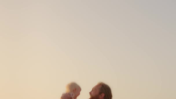 Adult Caucasian bearded father playing with son daughter infant child outdoors happy family kid newborn toddler fly in air dad throws baby up in sky in summer parent and small girl play toss up game - Imágenes, Vídeo