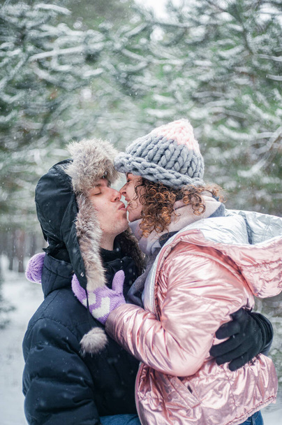 Young beautiful couple in winter forest. Happy couple has fun with snow. - Foto, Imagen