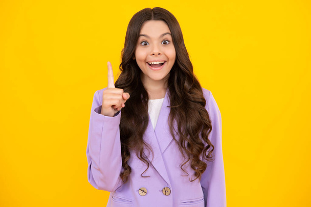 Surprised teenager girl. Funny face of young teenager pointing up with finger, isolated on yellow background. Girl has great new idea - Fotó, kép