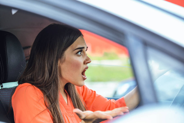 Une conductrice stressée assise dans sa voiture. Une conductrice en colère conduisant une voiture. Une jeune femme en colère coincée dans un embouteillage. Femme agacée en voiture. Fille coincée dans la circulation
. - Photo, image