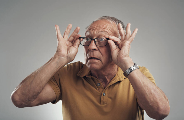 Like my new specs. Studio shot of an elderly man adjusting his spectacles against a grey background - Foto, imagen