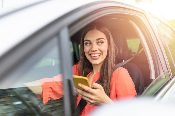 Woman driver using a smart phone in car. Woman driver using a smart phone in car. Leisure, road trip, technology, travel and people concept - Happy woman driving car with smartphone - Foto, Imagen