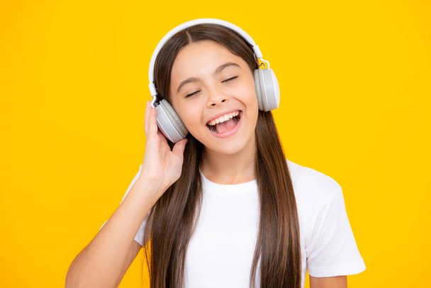 Child music concept. Teenager child girl dances in rhythm of melody, listens song in headphones. Child listening to music through earphones - Foto, Imagen