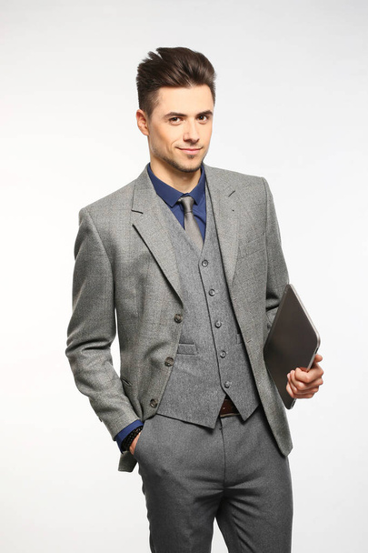 Attraente uomo d'affari che sorride e tiene il tablet mentre indossa una cravatta rossa e un vestito blu, in piedi su sfondo bianco dello studio
 - Foto, immagini