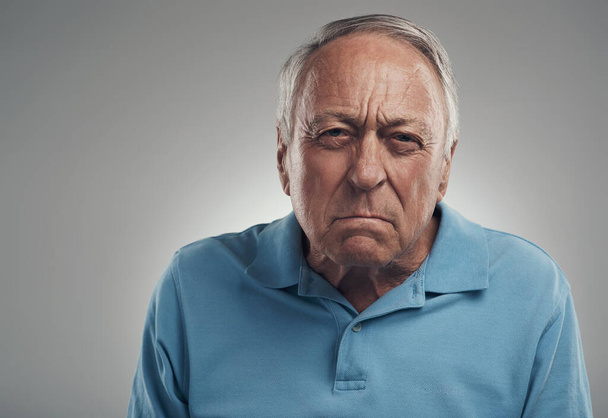 You make me so angry. an old man looking angrily at the camera in a studio against a grey background - Photo, image