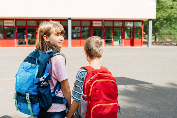 A boy and a girl, brother and sister with backpacks on their backs go to school together in an embrace. Beginning of the school year. Children are happy to learn. - Foto, Imagem