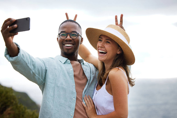 Make the good times last a long time. a happy young couple taking selfies on a road trip along the coast - Foto, afbeelding