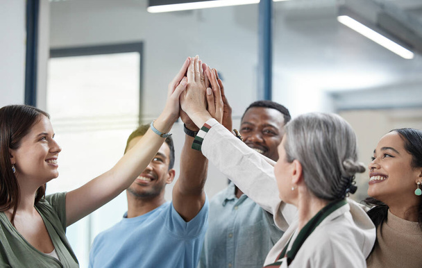 Our aim is to win this together. a group of businesspeople giving each other a high five in an office - Фото, изображение