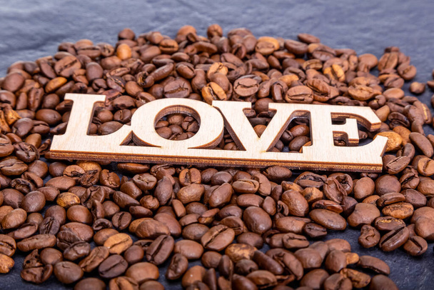 Крупный план кофейных зерен в форме сердца и надпись любовь. - Фото, изображение