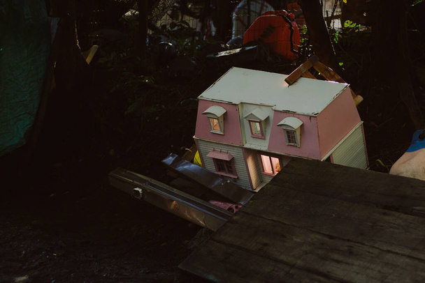 Children's doll house lit up in a garbage pile - Fotó, kép