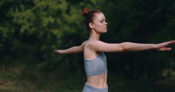 A woman warms up her body before a workout in nature. The concept of an athletic body and health. High quality 4k footage - Video