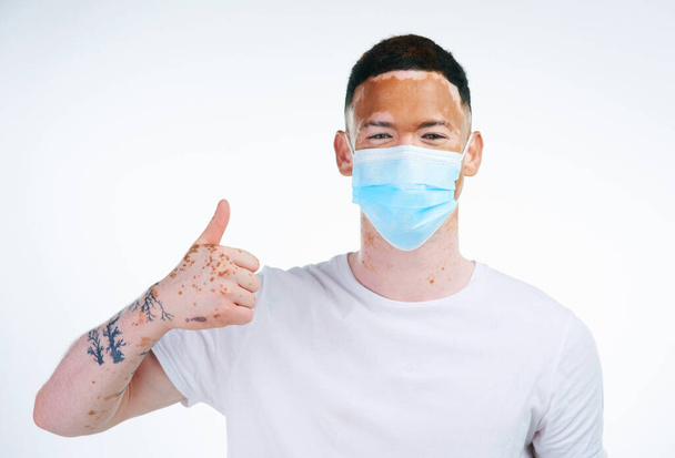By caring for myself, Im caring for you too. Portrait shot of a young man with vitiligo wearing a protective facemask posing on a white background - Foto, afbeelding