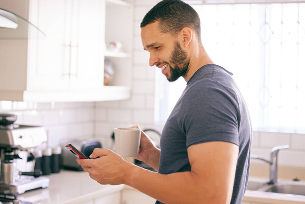 Starting the day the right way with caffeine. a young man holding a coffee cup while texting - Photo, Image
